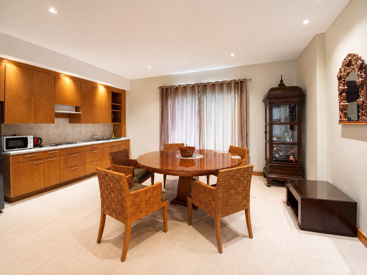 Round dining table with woven chairs beside an antique cabinet