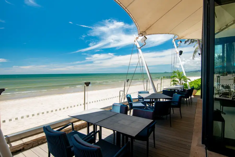 Tables on the Sheraton beachfront terrace under a white canopy, with the sea beyond