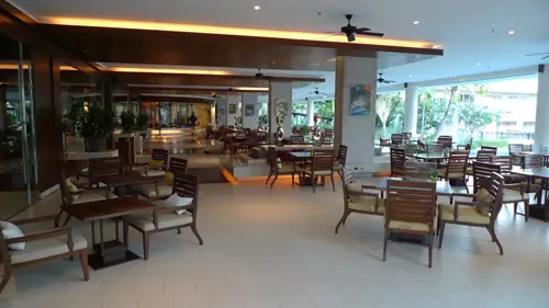 An airy indoor Sheraton dining room with wooden tables and open walls