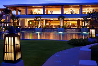 A Sheraton restaurant terrace beside the pool, lit in the evening