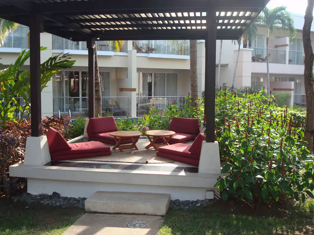 A shaded Sheraton garden pavilion with cushioned seating beside the pool