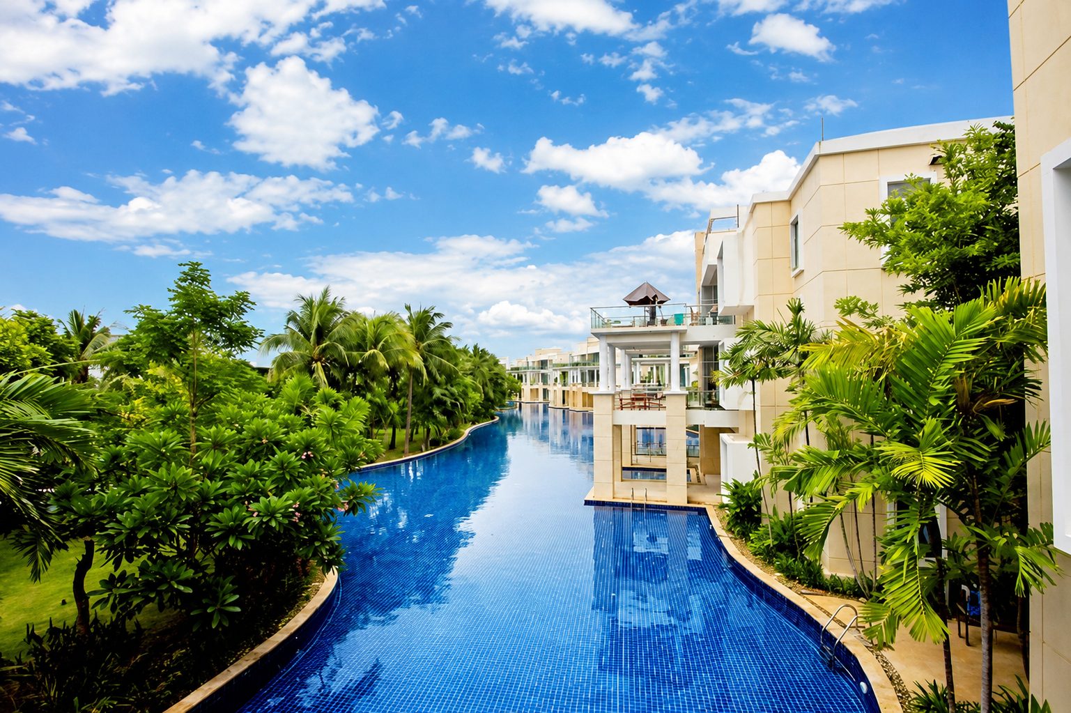 Elevated view of the lagoon pool winding between the residence buildings and palms